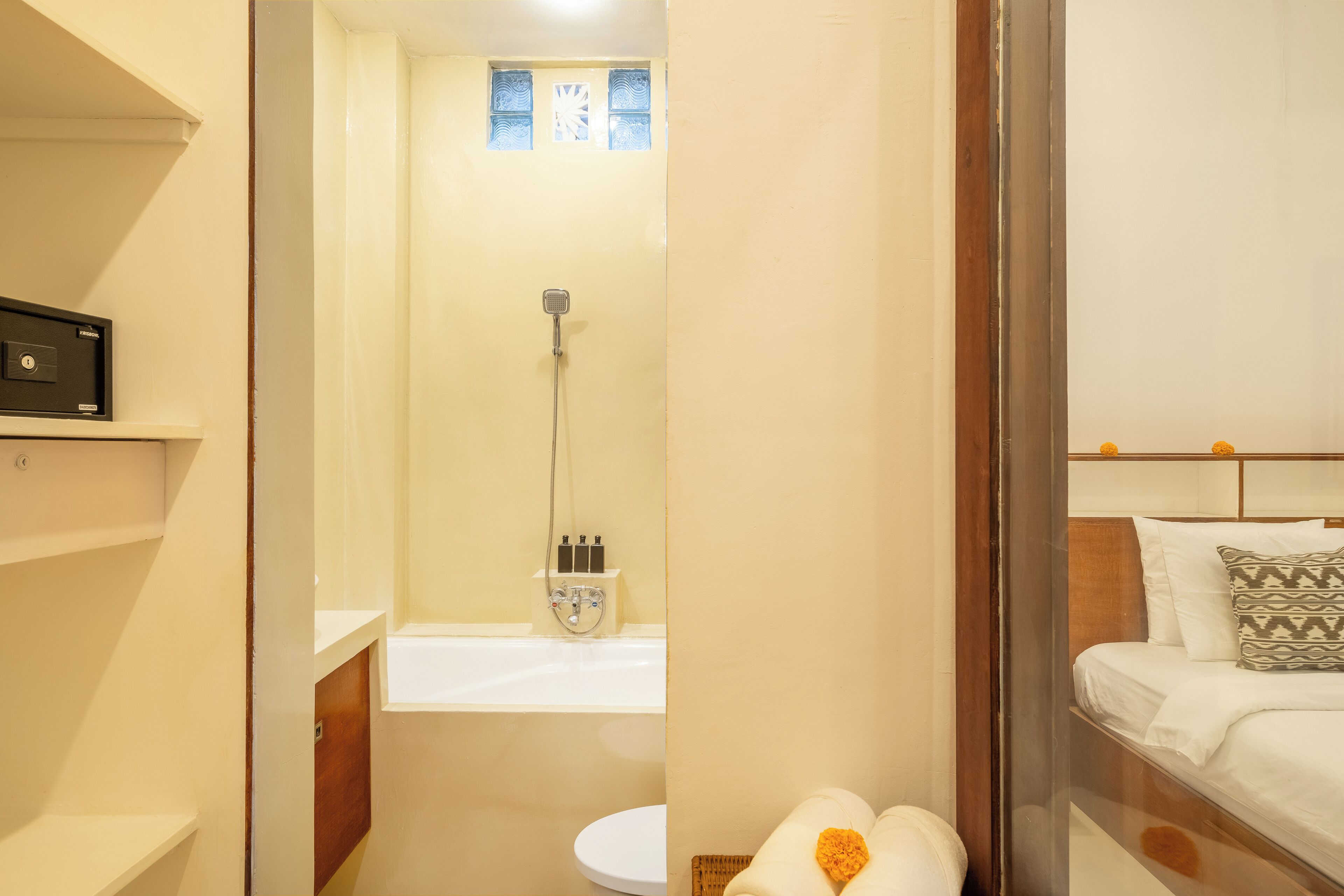 A bathroom with a shower, toilet, and a bed with pillows.