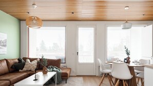 Een moderne woonkamer met een bruine leren bank, een witte salontafel en een eetgedeelte met een houten tafel en stoelen.