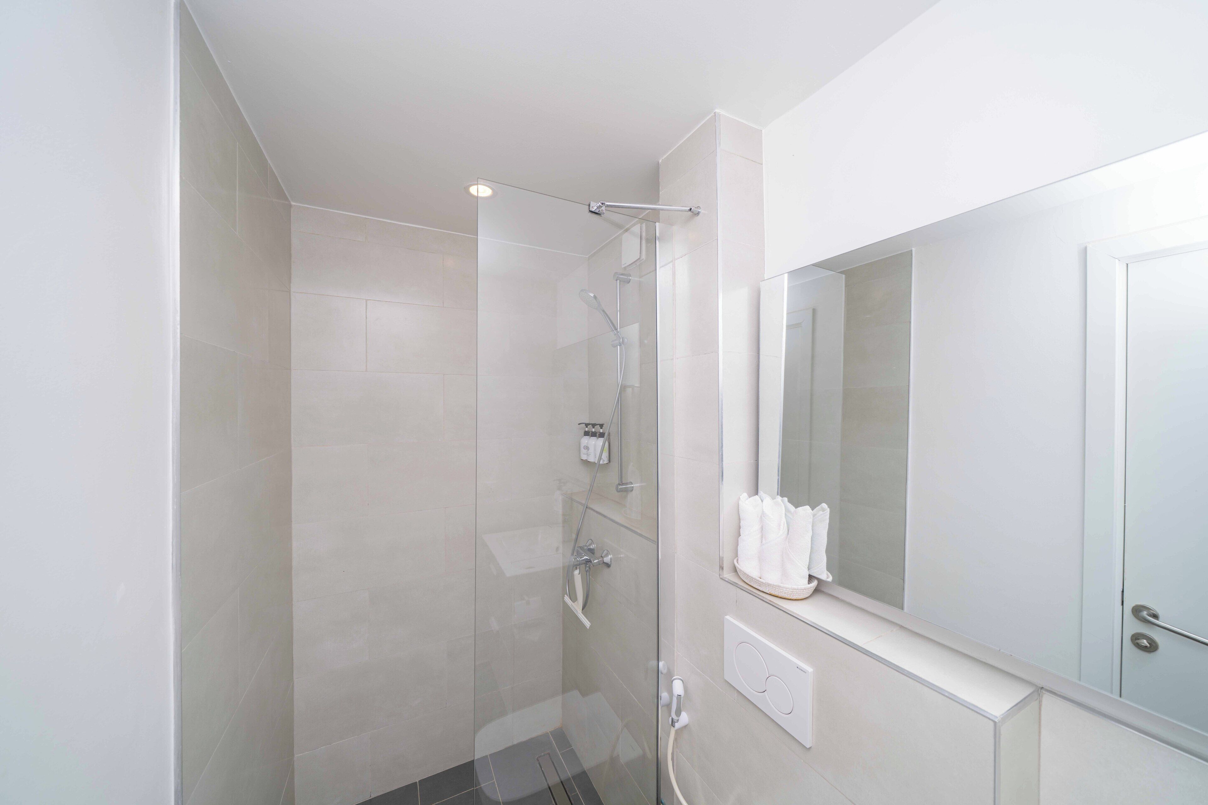 Un baño moderno con cabina de ducha de vidrio, un espejo grande y un perchero para toallas.