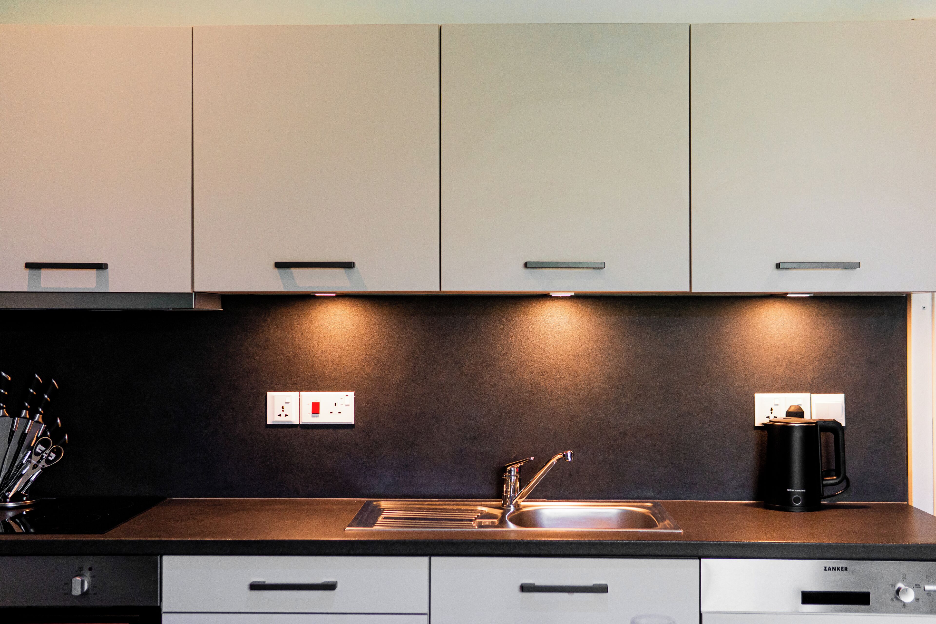 Een moderne keuken met een donker aanrecht, een roestvrijstalen spoelbak en een koffiezetapparaat.