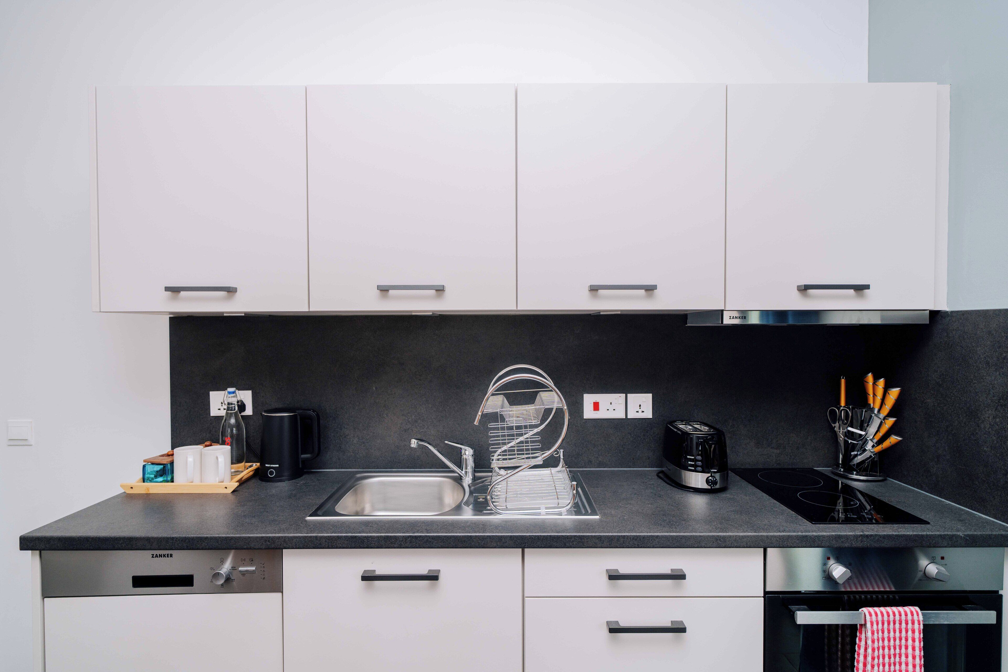 A modern kitchen with a black countertop, stainless steel appliances, and white cabinetry.