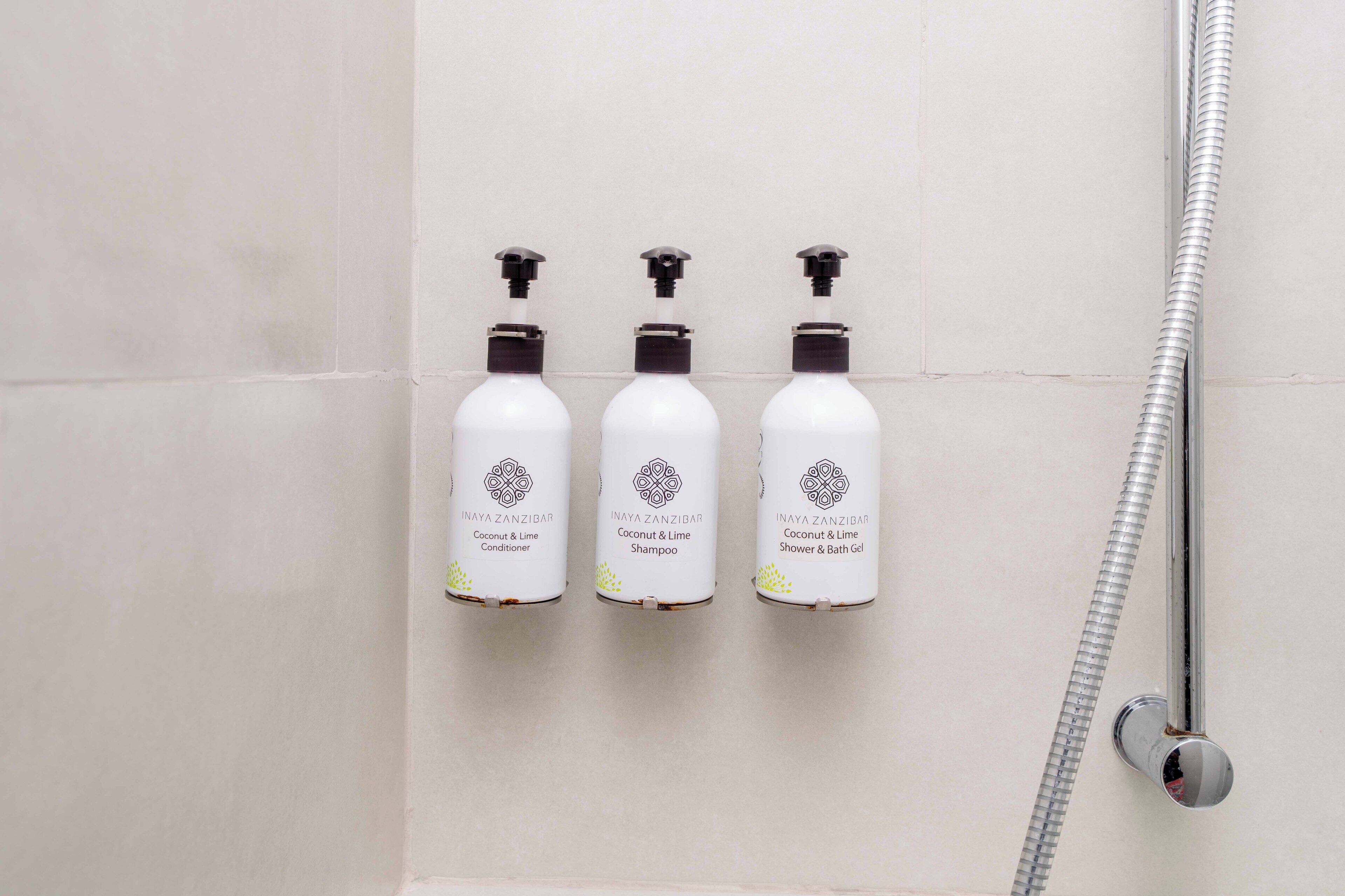 Trois bouteilles de produits Inaya Zanzibar aux parfums de noix de coco et de citron vert sont posées sur un mur.