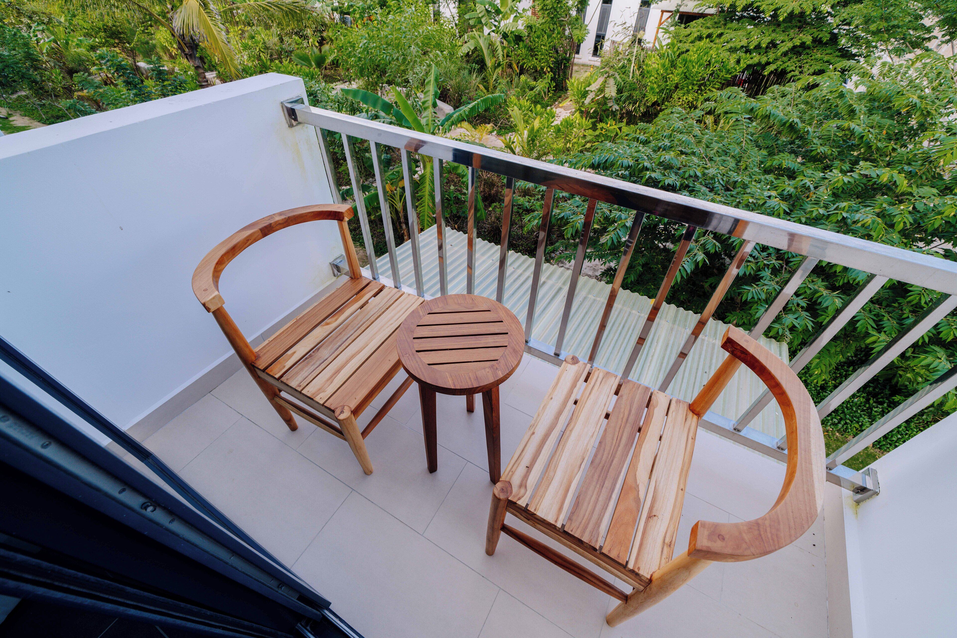 Een balkon met twee houten stoelen en een kleine ronde tafel.