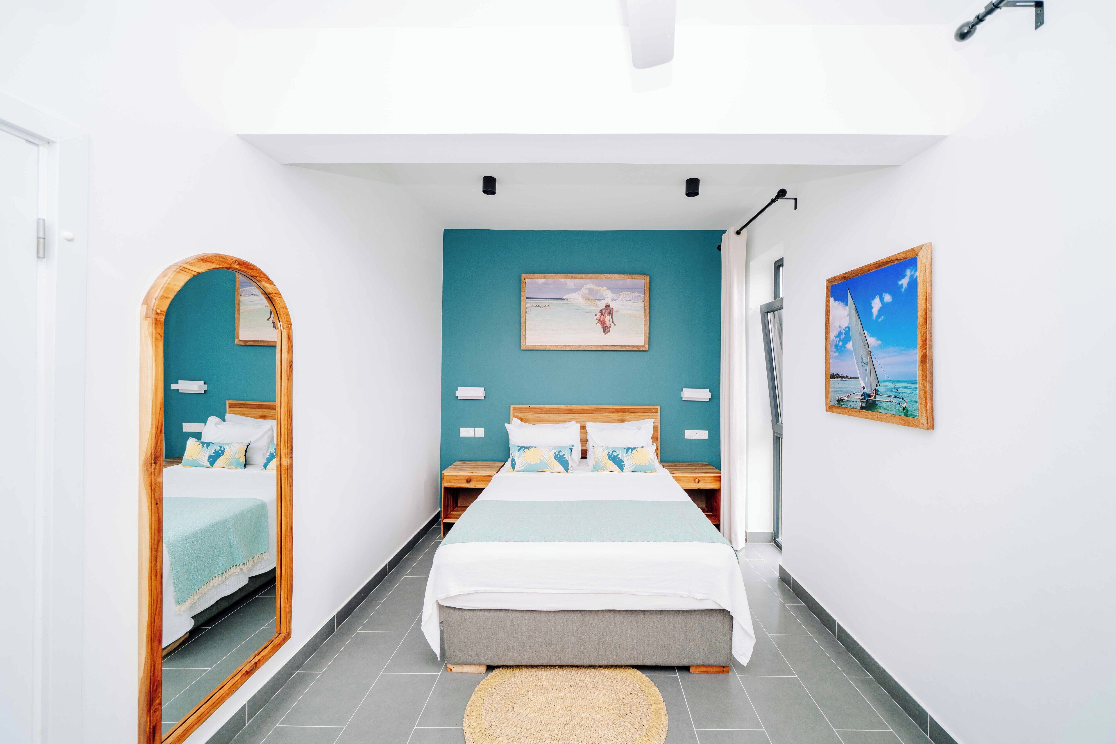 Un dormitorio con cama, mesitas de noche, un espejo y obras de arte en las paredes.