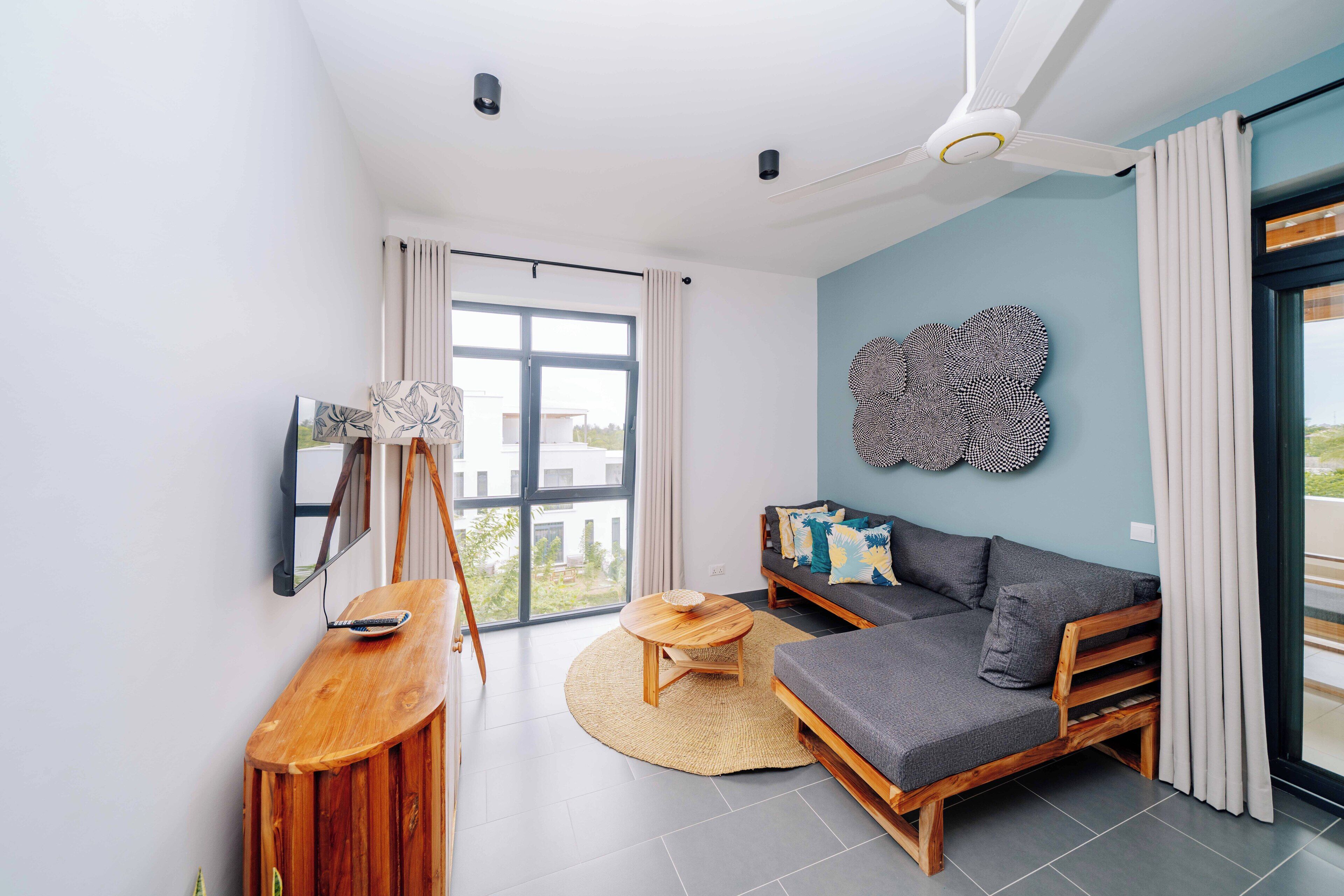 A modern living room with a sofa, a wooden coffee table, and a large window.