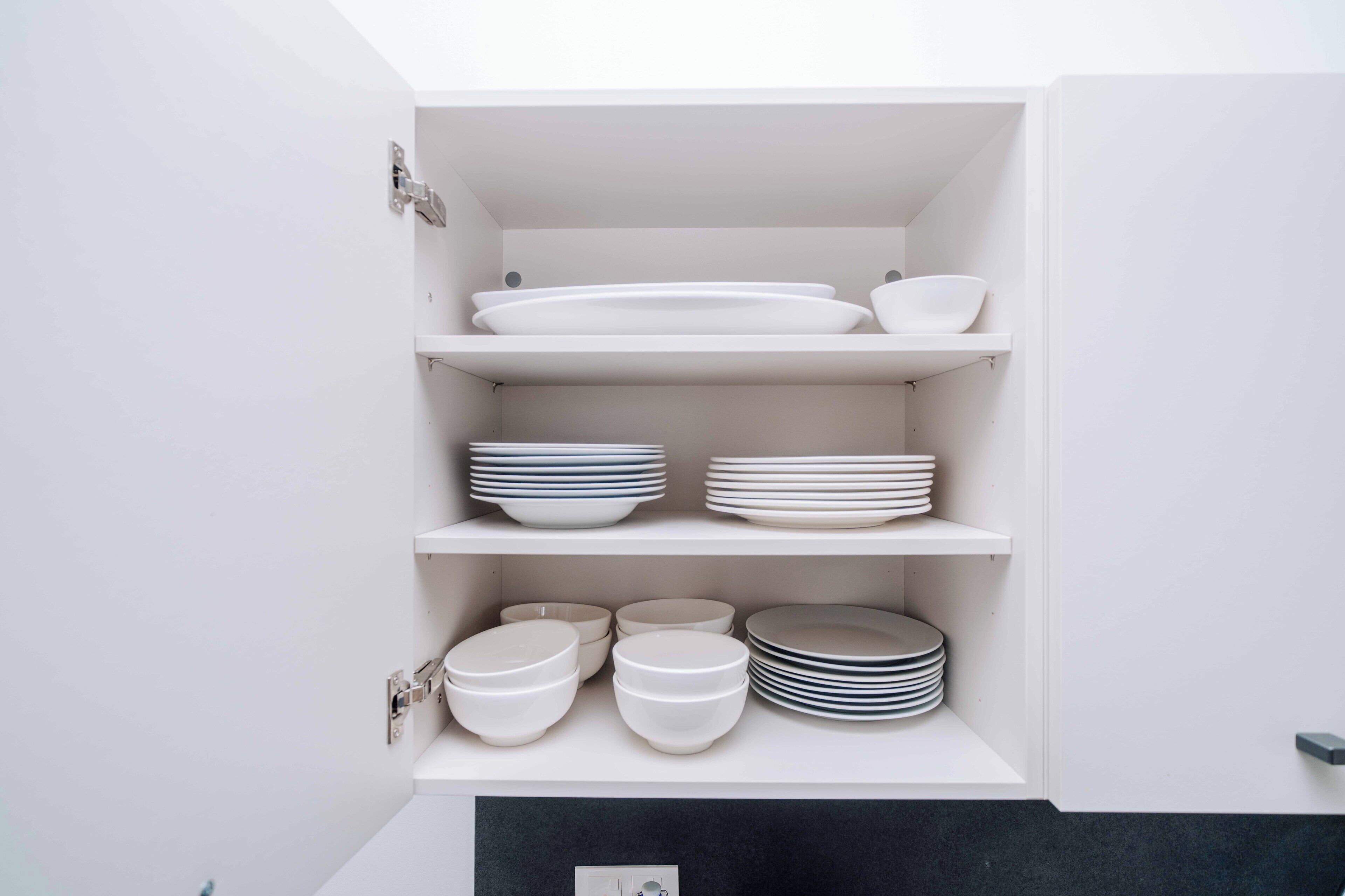 Un armario blanco con estantes que exhiben distintos platos y cuencos blancos y azules.