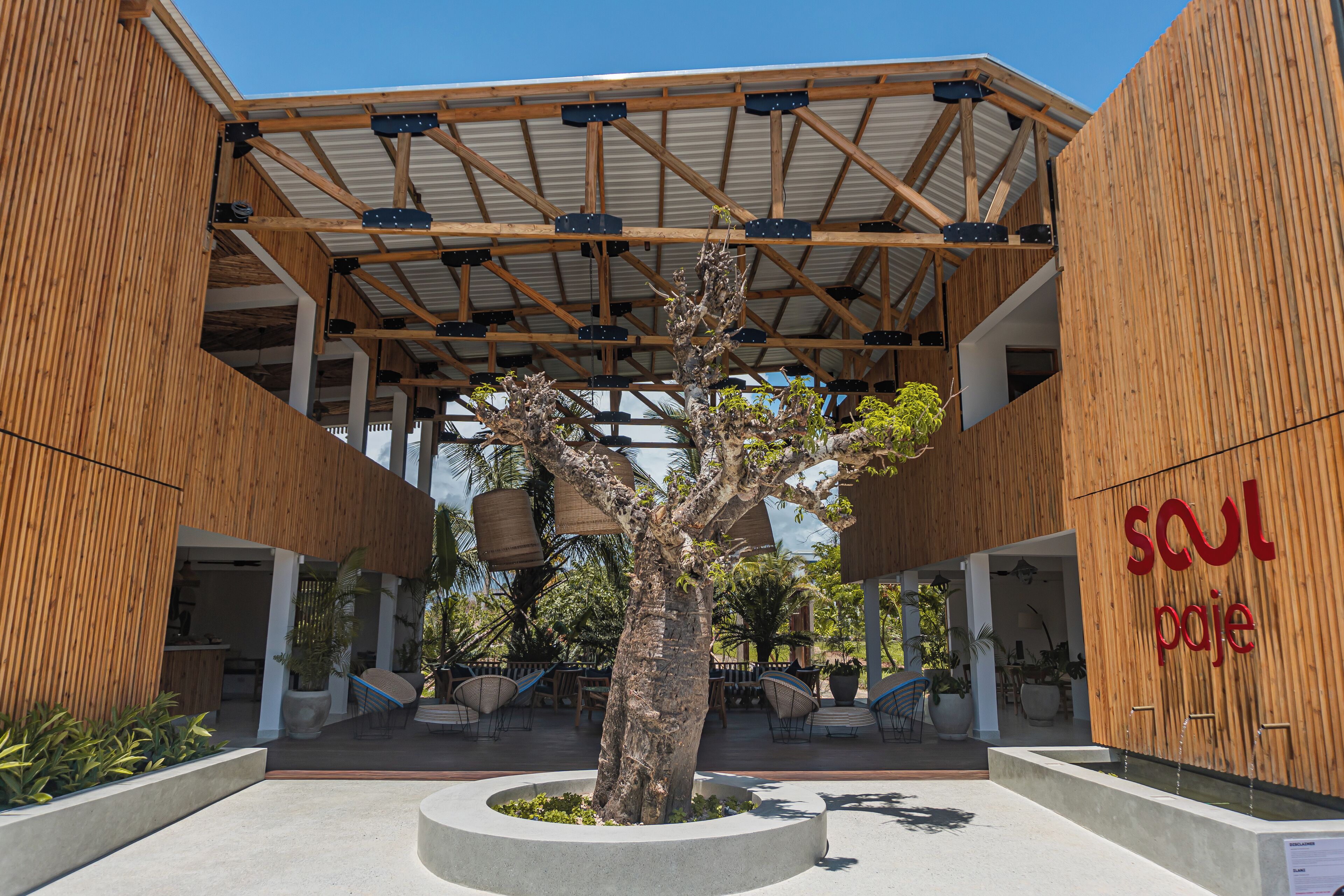 A modern building with a wooden facade, a covered outdoor area with seating, and a sign that reads "soul pojé".