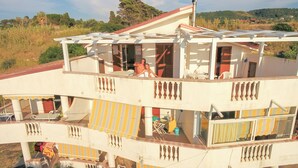 Un edificio a più piani con balconi, area salotto esterna e vista sul paesaggio circostante.