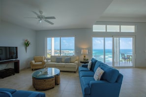 Relax in this stylish living room with a large flat-screen TV, comfortable seating, and a beautiful ocean view.