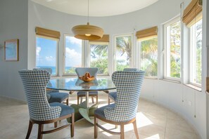 Enjoy meals in this cozy dining area with a round table and four chairs, surrounded by a curved ceiling and large windows.