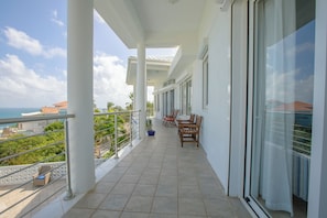 Enjoy the ocean view from this balcony with a seating area and potted plant.