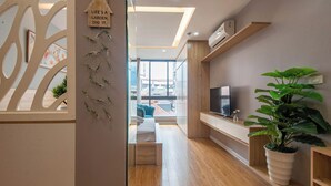 Una sala de estar moderna con televisor, piso de madera, una planta grande en maceta y un cartel en la pared.