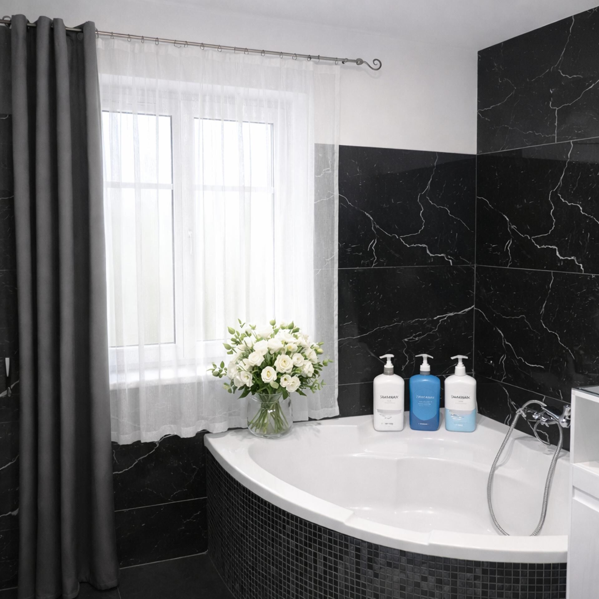 Um banheiro moderno com uma banheira separada, uma janela com cortinas leves e um vaso com flores brancas.