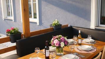 A dining table set with plates, glasses, and cutlery, surrounded by wooden chairs.