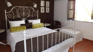 A bedroom with a white metal bed frame, a brown headboard, and a window with curtains. - Quinta do Xarrama (Évora)