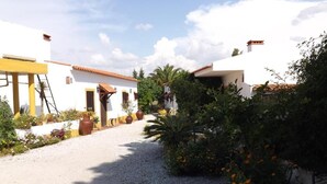 A courtyard with white buildings, a gravel path, and potted plants. - Quinta do Xarrama (Évora)