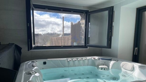 Ein modernes Badezimmer mit einer großen Badewanne, einem Fenster mit Aussicht und einem Spiegel über der Wanne.