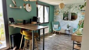 Eine moderne Küche mit einem Holztisch und Barhocker, einem blauen Sessel und einer Steinwand mit Spiegel.