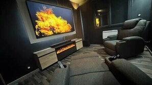 Ein modernes Wohnzimmer mit Flachbildfernseher, Kamin und bequemer Couch.