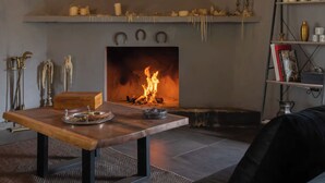 Ein gemütliches Wohnzimmer mit Kamin, Holztisch und Bücherregal.