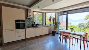 Una cocina moderna con comedor, ventanas amplias y vistas a la vegetación.
