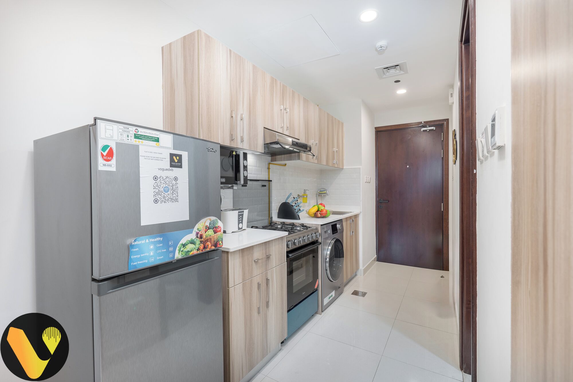 A compact kitchen with a refrigerator, microwave, oven, and sink.