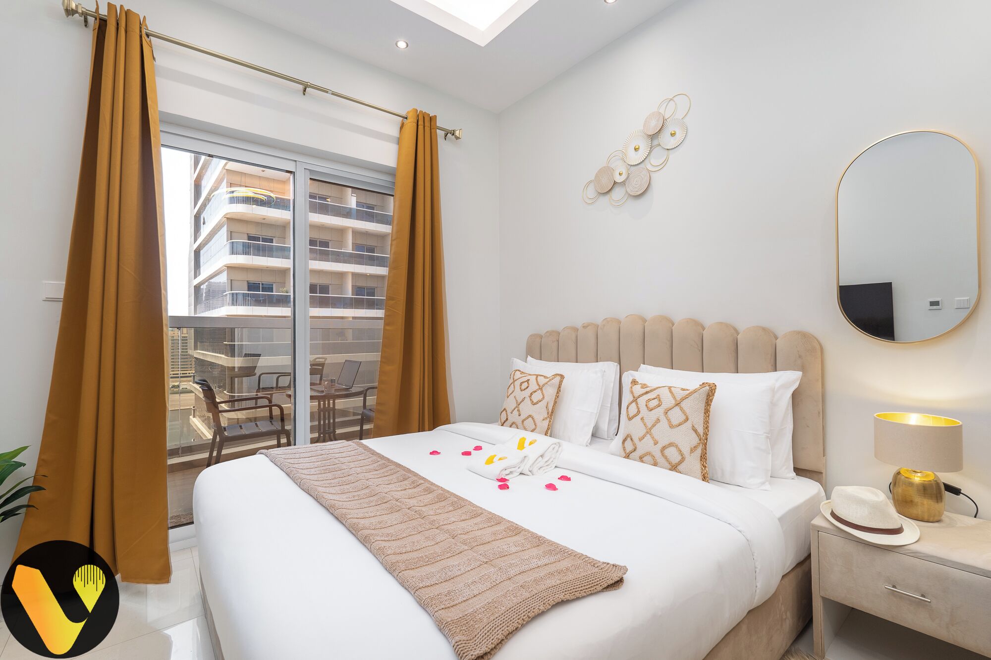 Une chambre d’hôtel avec un lit, une table de chevet, une lampe, un miroir et une vue sur le balcon extérieur.