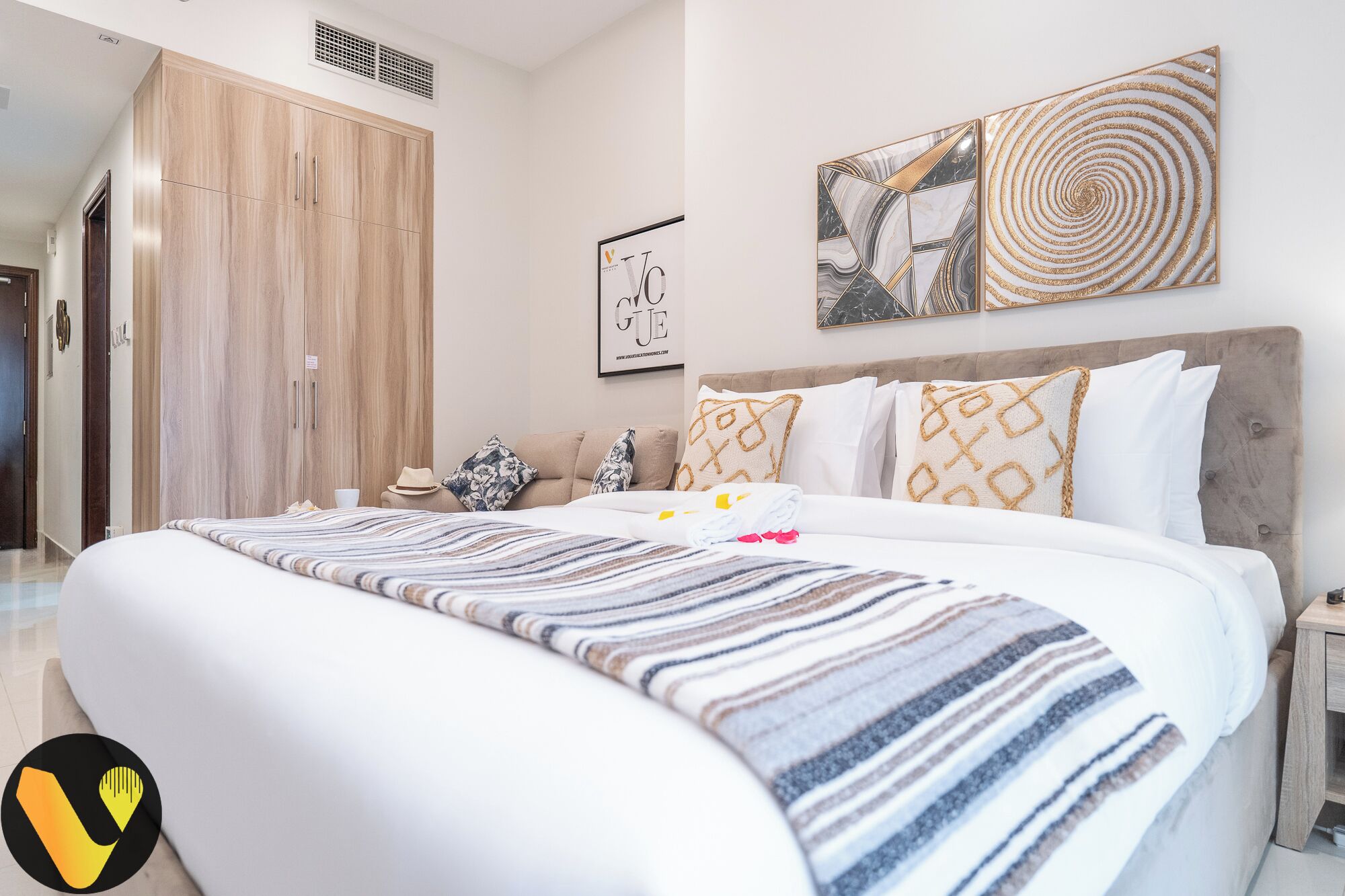 Une chambre d’hôtel avec un grand lit, une armoire, une tête de lit et un mur orné d’un tableau encadré.