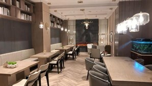 A restaurant with a long counter, multiple seating options, a fireplace, and a fish tank. - Yinjiang PLUS Hotel (Hangzhou)