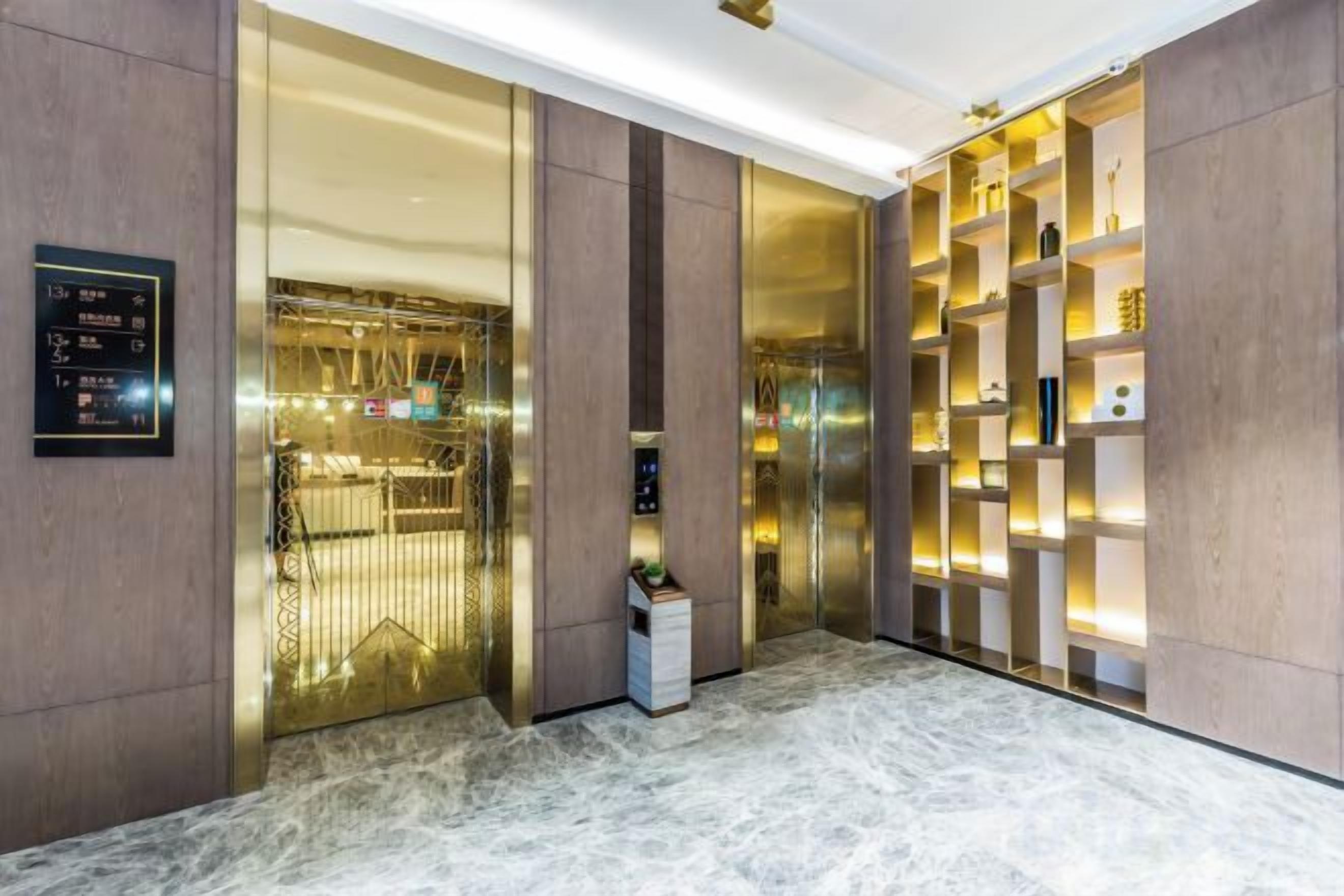 A hotel lobby with a marble floor, a reception desk, and a wall-mounted shelf with decorative items.