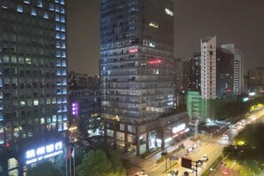 A nighttime cityscape with high-rise buildings, illuminated windows, and a busy street with vehicles. - Yinjiang PLUS Hotel (Hangzhou)
