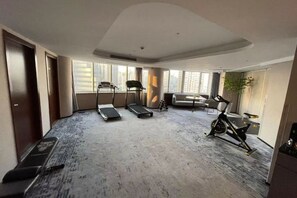 A spacious room with a treadmill, stationary bike, and a sofa. - Yinjiang PLUS Hotel (Hangzhou)