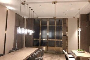 A modern conference room with a long table, chairs, hanging pendant lights, and a large glass door. - Yinjiang PLUS Hotel (Hangzhou)