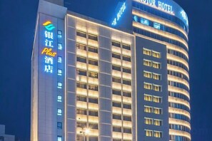 A hotel with a curved facade, multiple floors, and illuminated windows. - Yinjiang PLUS Hotel (Hangzhou)