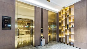 A modern elevator with a glass door, a digital display, and a small plant on the floor. - Yinjiang PLUS Hotel (Hangzhou)