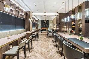 A modern dining area with wooden flooring, multiple tables and chairs, and pendant lighting. - Yinjiang PLUS Hotel (Hangzhou)