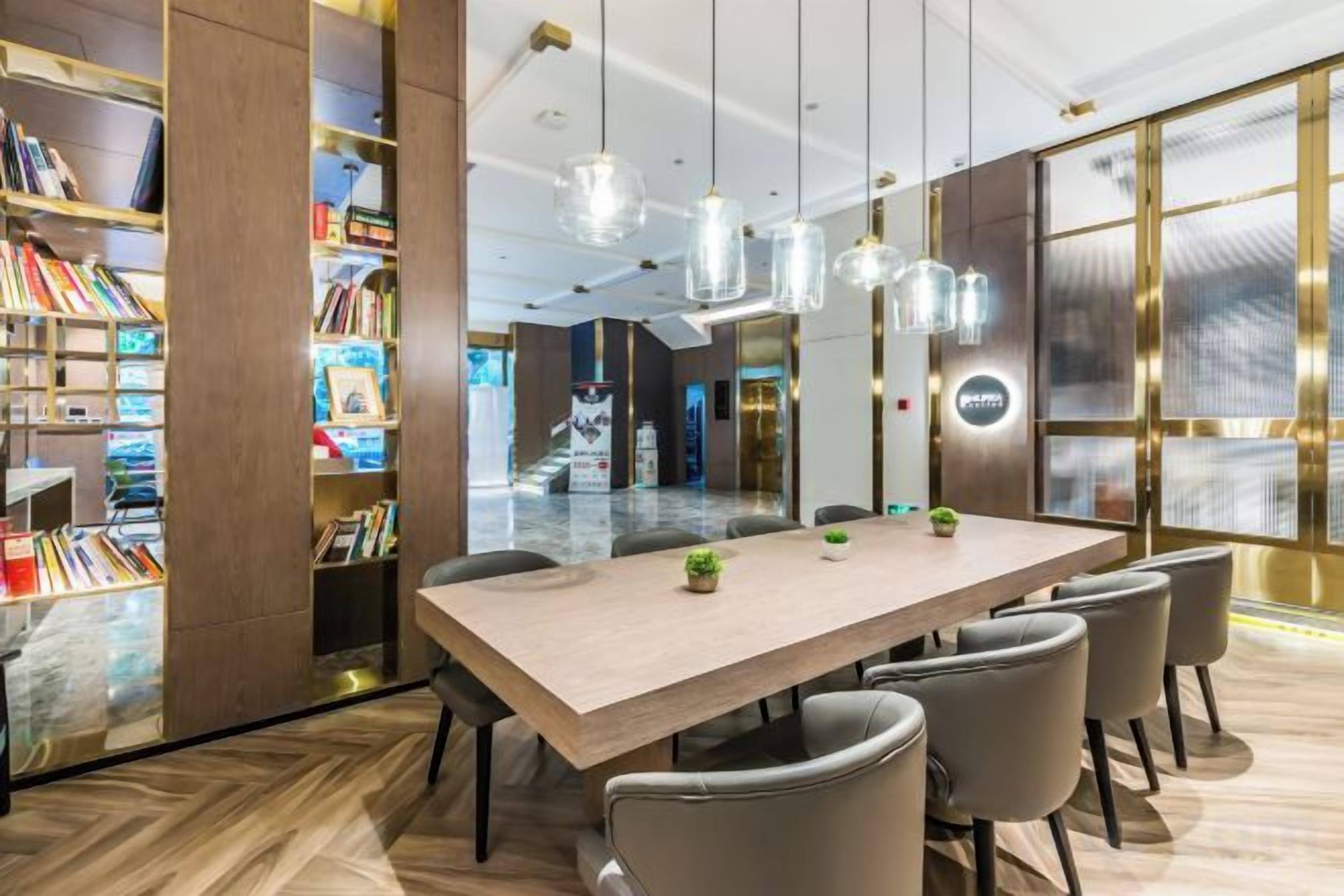 A modern conference room with a long table, chairs, and a bookshelf filled with books.