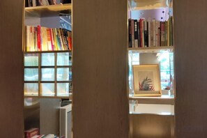 A bookshelf with books and a framed picture. - Yinjiang PLUS Hotel (Hangzhou)