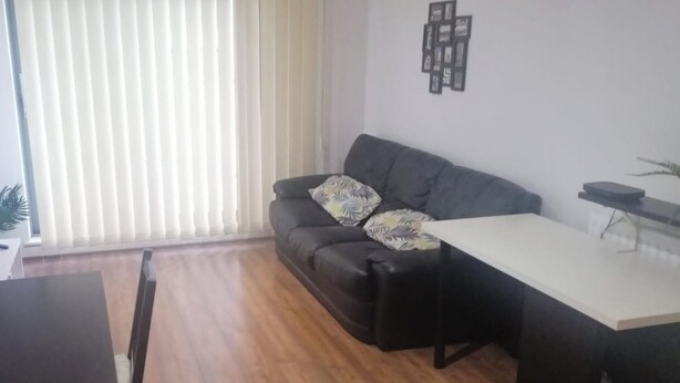 A living room with a dark leather sofa, a white coffee table, and a wooden floor.