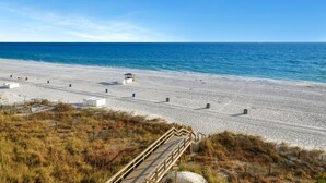 A beach with a wooden walkway leading to the water, a lifeguard tower, and a sandy area with scattered objects. - Majestic Beach Towers 2-404 (Panama City Beach)