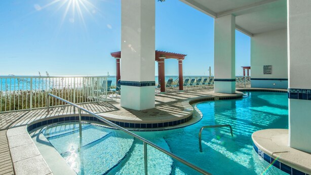 An indoor swimming pool with a view of the ocean, surrounded by white pillars and a pergola. - Majestic Beach Towers 2-404 (Panama City Beach)
