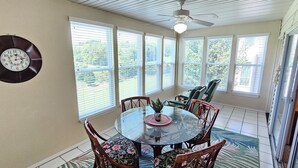A dining area with a round glass table, wicker chairs, and a clock on the wall. - Fairways Paradise Walk-in Suite at the Fairways at Thousand Hills! Great Rates! (Branson)