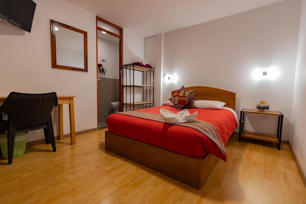 Ein Schlafzimmer mit einem hölzernen Bett, einem Nachttisch, einem Sessel, einem Spiegel und einem Kleiderschrank.