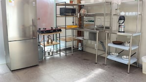 Een moderne keuken met roestvrijstalen apparatuur, metalen planken en een gasfornuis.