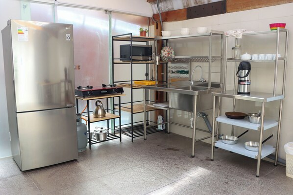A modern kitchen with stainless steel appliances, metal shelving, and a gas stove. - Andes House Cusco (Cusco)