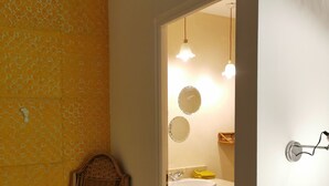 Une salle de bain avec un fauteuil en osier, un lavabo et un miroir.