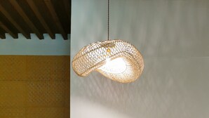Une pièce comprenant un lit, un luminaire suspendu, une chaise et un mur orné d’un motif décoratif.