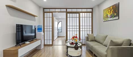 A modern living room with a flat-screen TV, a sofa, a coffee table with a vase, and a water dispenser.