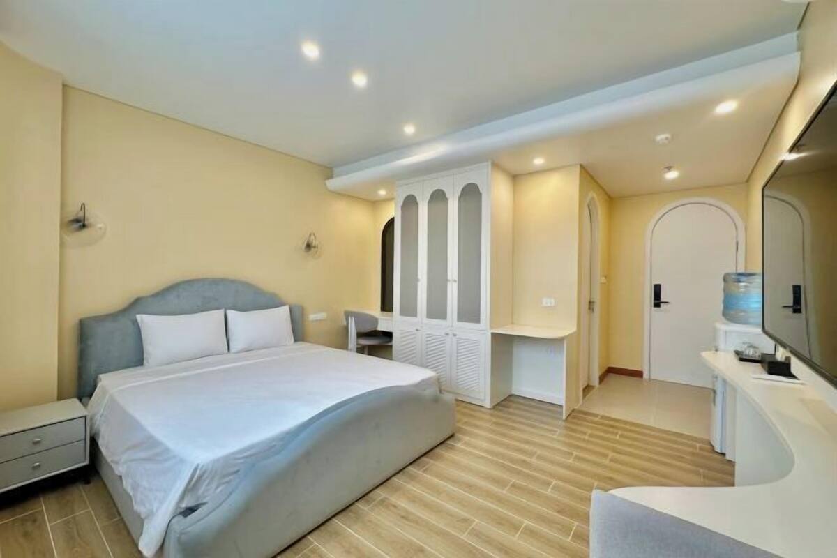 A bedroom with a bed, a desk, a chair, a wardrobe, and a bathroom.