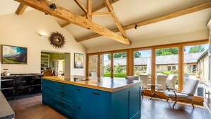 Una cocina amplia con una isla grande, vigas de madera y vista al jardín.